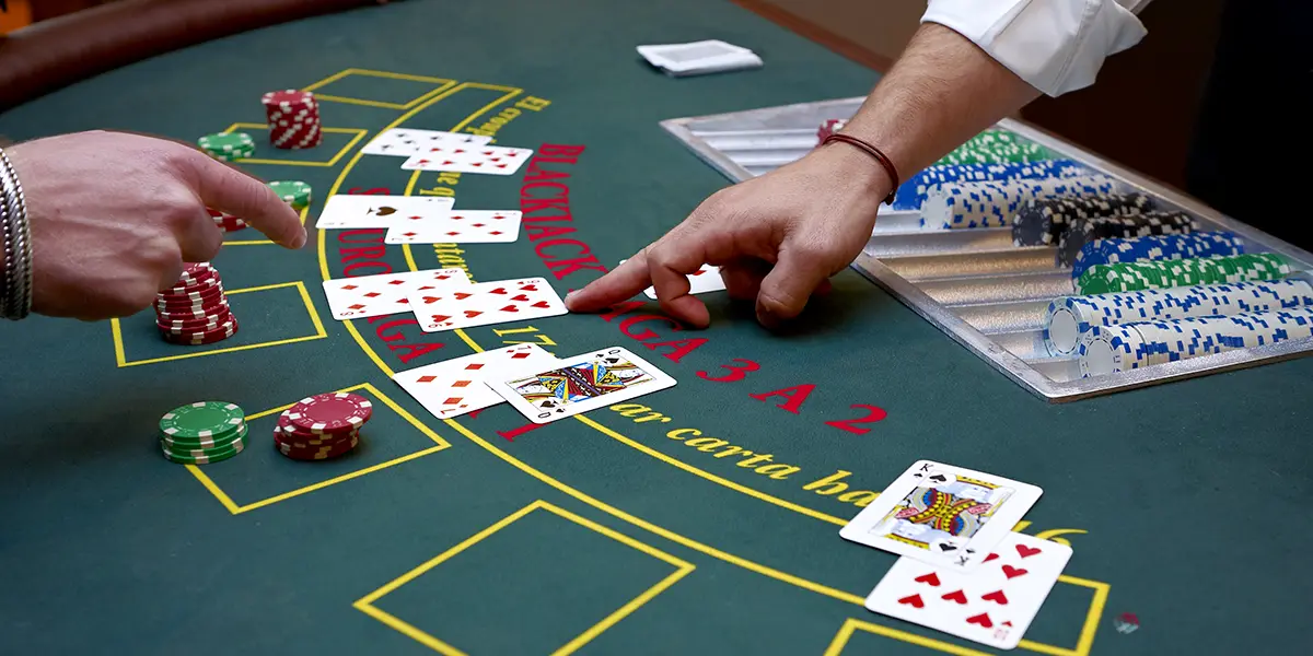 Spieler zeigt beim Blackjack auf seinen Stapel mit zwei Karten