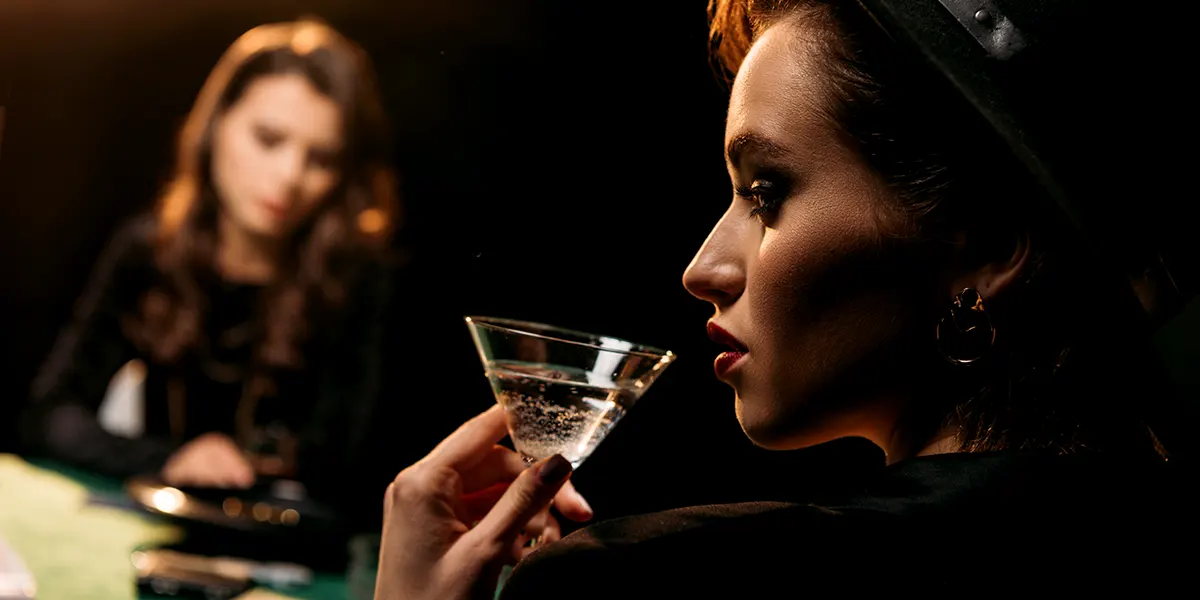 Mysteriös wirkende Frau mit Cocktail am Casino-Tisch