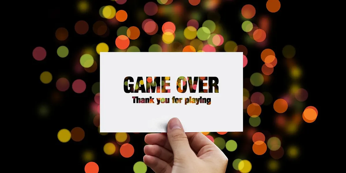 Hand hält Zettel mit dem Text "Game Over, thank you for playing" in die Luft