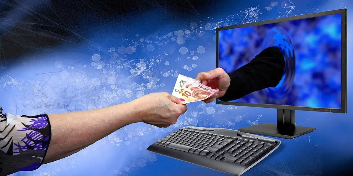 Hand überreicht Geld durch einen Computer-Bildschirm