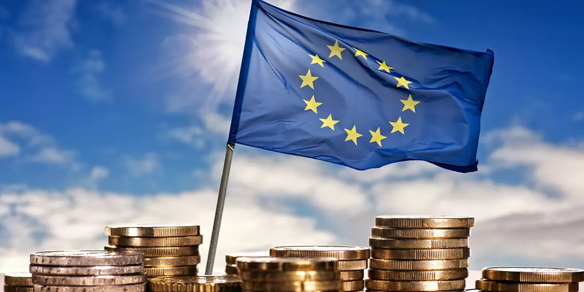 EU Flagge umgeben von Münzen vor blauem Himmel