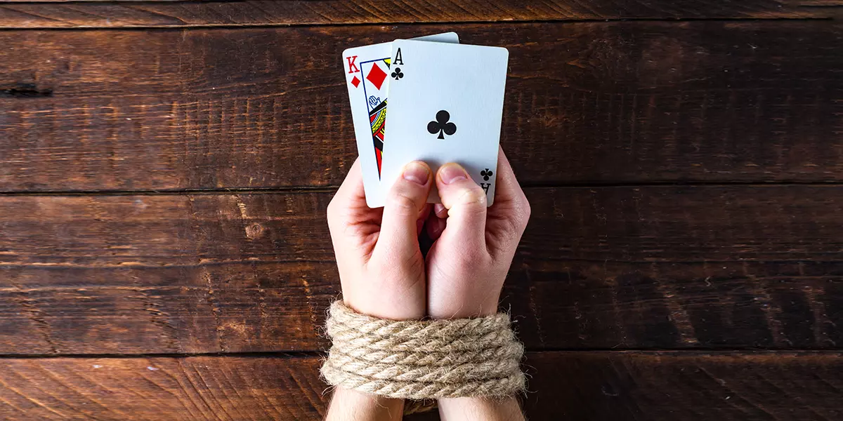 Gefesselte Hände mit Pokerkarten