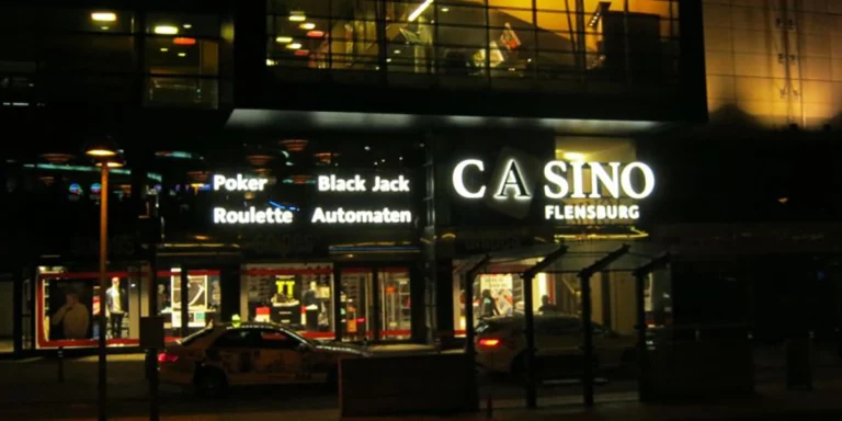 Die Spielbank Flensburg von außen bei Nacht mit Leuchtschrift-Werbung für Poker, Roulette, Black Jack und Automaten