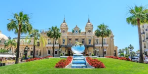 Das Casino Monte-Carlo von außen mit Palmen, Blumenbeeten, Rasen und Springbrunnen davor