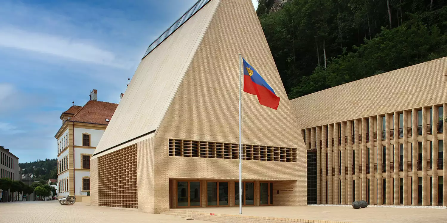 Das Landtagsgebäude des Fürstentums Liechtenstein von außen mit der gehissten Staatsflagge davor
