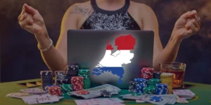 Frau sitzt mit gedrückten Daumen und einem Laptop mit niederländischer Flagge auf dem Cover an einem Spieltisch mit Karten und Poker-Chips