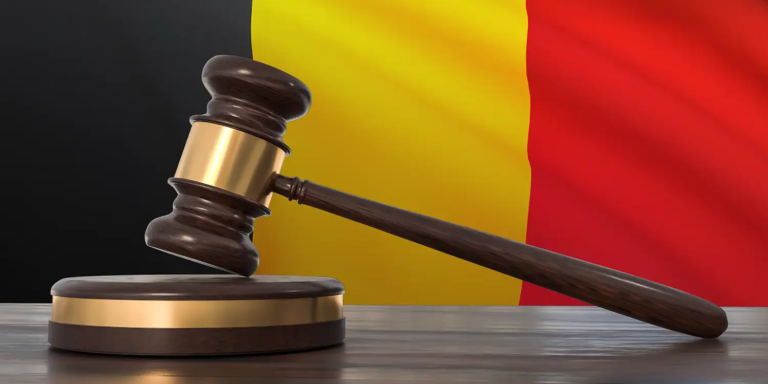Richterhammer auf Tisch vor belgischer Flagge im Hintergrund