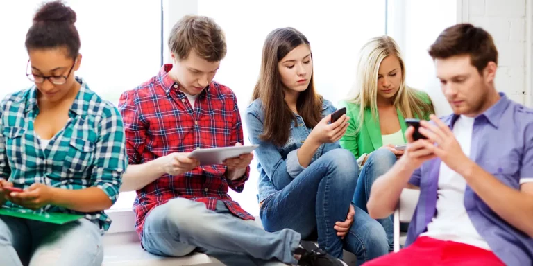 Mehrere Jugendliche mit Mobiltelefonen und Tablets in den Händen