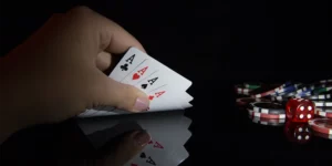 Hand hält 4 Asse, daneben Pokerchips