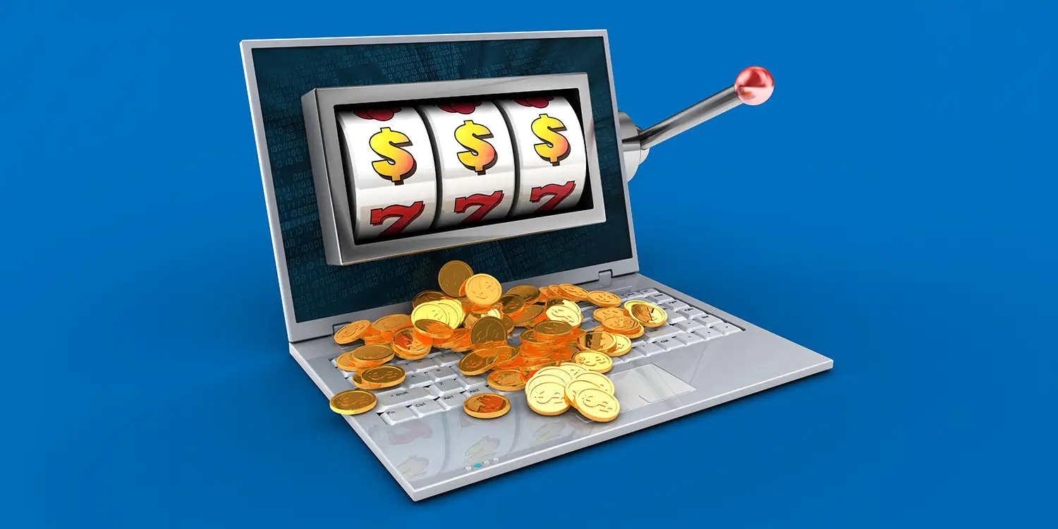 Laptop mit Slot auf dem Bildschirm und mit Goldmünzen auf der Tastatur