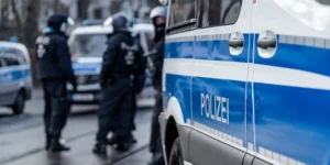 Polizisten neben Polizeiwagen