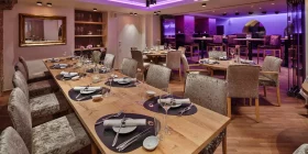 Restaurantbereich mit eingedeckten Holztischen und eleganten Polsterstühlen