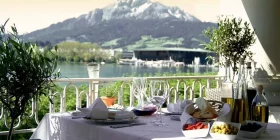 Elegant gedeckter Tisch auf Casino-Terrasse mit Blick auf Berge und einen See