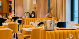 Elegant gedeckte Tische mit gelben Möbeln und Eimern mit Champagner-Flaschen