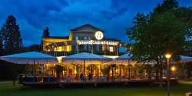 Das stimmungsvoll beleuchtete Grand Casino Baden und seine Restaurant-Terrasse von außen bei Nacht