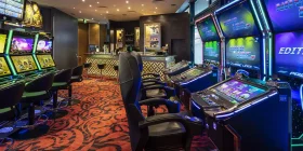 Raum mit mehreren Spielautomaten und einer Bar im Hintergrund