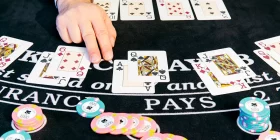 Hand zwischen Spielkarten und Chips auf Black Jack Tisch