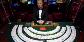 Croupier am Black Jack Tisch mit ausgebreiteten Kartendecks