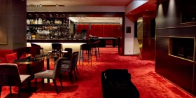 Barbereich mit elegantem roten Teppich und schwarzen Sitzmöbeln