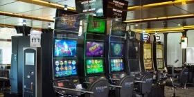 Diverse Spielautomaten nebenbeinander und Anzeigetafel mit aktuellem Stand des Mystery Jackpots